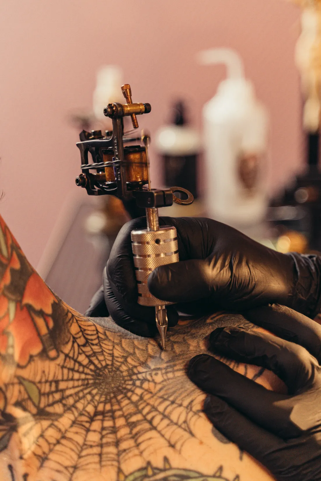 A tattoo machine at work over a fine black-line piece on a client's skin